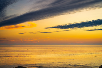 Naklejka premium Lighthouse seascape at the beach at sunset along the rocky shoreline
