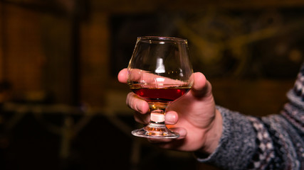 Close-up of persons hand holding glass with whiskey or bourbon.