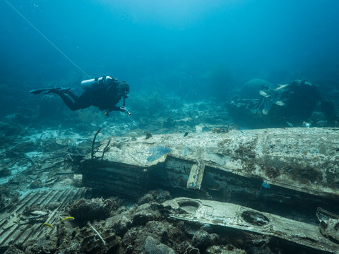Diver around Elvin's Plane Wreck in coral reef of Caribbean sea around Curacao