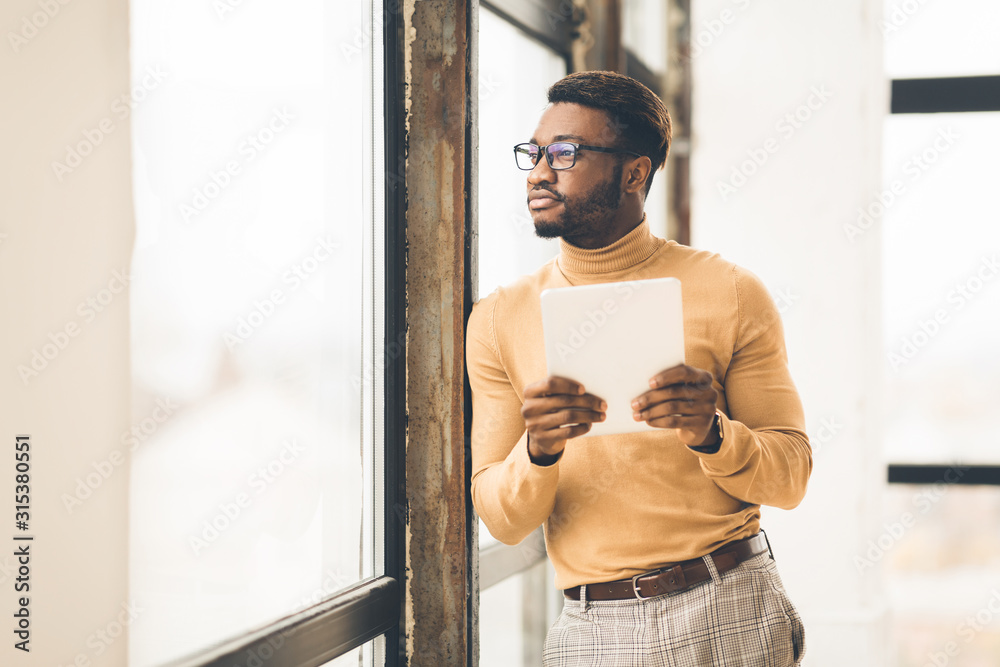 Poster dreaming afro manager using tablet looking away