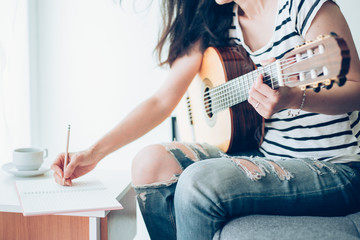 artist songwriter thinking writing notes,lyrics in book at studio.man playing live acoustic guitar...