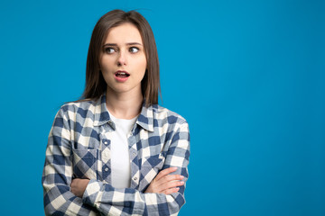 Fototapeta premium Shocked girl with crossed arms looking away with open mouth