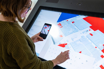 	 Woman with phone uses self-service kiosk in the shopping mall	 - obrazy, fototapety, plakaty