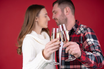 Selective focus of couple holding glasses of champagne isolated on red background