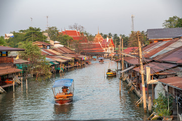 Fototapeta na wymiar Wooden boats busy ferrying people at Amphawa floating market in Bangkok. A traditional popular method of buying and selling still practiced in Amphawa canals of Thailand