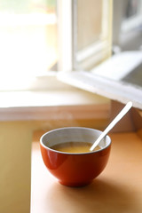 Bowl of homemade pumpkin soup by the window. Selective focus.