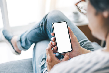 Mockup image blank white screen cell phone.man hand holding texting using mobile sitting at coffee...