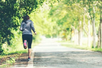 Gartenposter Sportlicher asiatischer Frauenläufer, der durch die Straße läuft und joggt. Outdoor-Training in einem Park. Gewichtsverlust und gesundes Konzept © freebird7977
