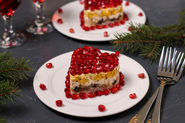 Festive salad in layers in the shape of a heart, decorated with pomegranate seeds on a dark background, Horizontal orientation