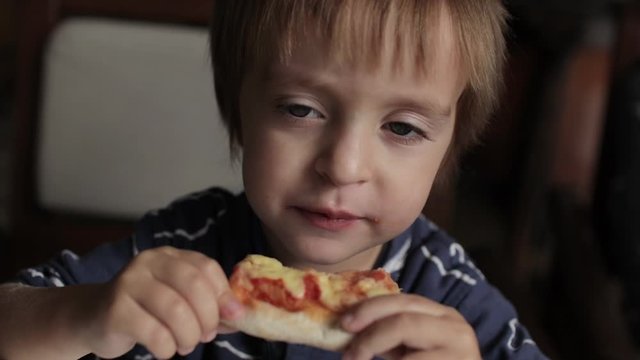 Close up of little cute boy eating pizza. Neutral colors for collor correction.
