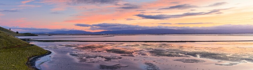 Panoramic views of Coyote Hills and salt evaporation ponds with Dumbarton Bridge in the background on winter sunset. Coyote Hills Regional Park, Alameda County, California, USA.