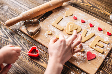 Cooking cookies from the dough in the shape of a heart and the word love. Baking for Valentine's day and a romantic date