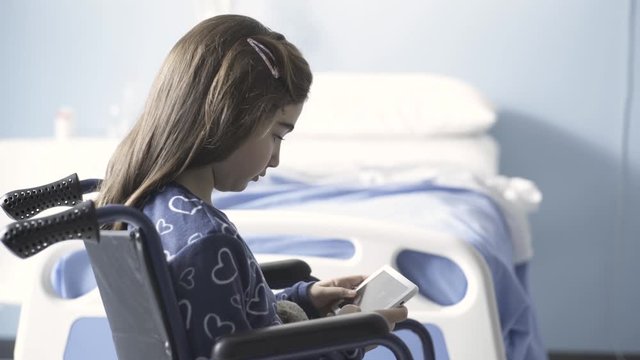 Girl in wheelchair using a digital tablet at the hospital