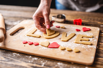 Cooking cookies from the dough in the shape of a heart and the word love. Baking for Valentine's day and a romantic date