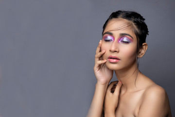 Obraz premium Closeup portrait of an Indian model with bold eye makeup and lipstick looking at camera. Makeup portrait for eye makeup and lipstick.