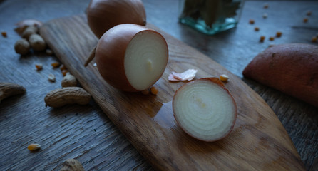Sweet potatoes and onions on a wooden cutting board. Still life