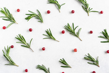 Pattern of fresh aromatic rosemary twigs and cranberries on white marble background. Flat lay...