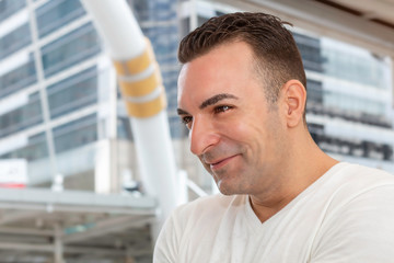 Cheerful Caucasian young man smiling and standing outdoors.