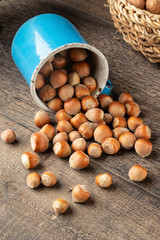 Hazelnuts spilled from a blue pot on a table