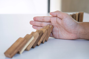 Risk and Strategy in Business, Image of hand stopping falling collapse wooden block dominoes effect from continuous toppled block, prevention and development to stability
