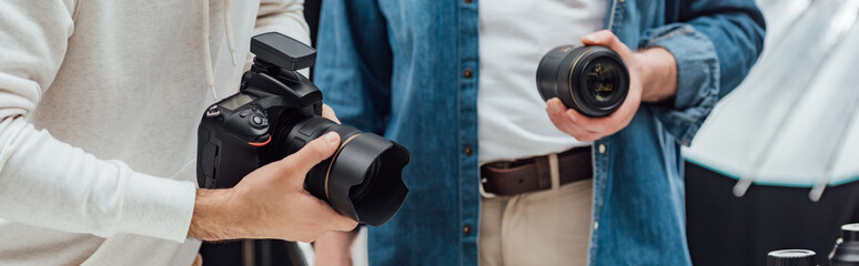 panoramic shot of art director holding photo lens near photographer