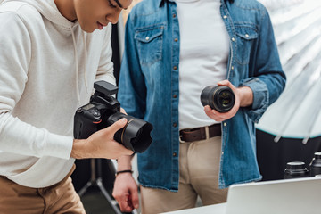 cropped view of art director holding photo lens near photographer