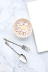 Boiled white rice in a cup with a spoon and white computer notebook with copy space top view - Flat lay
