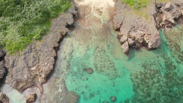 Aerial revealing shot from tropical turquoise water to a wide shot of agriculture fields, Miyakojima, Japan