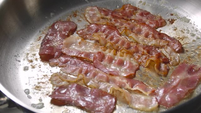 Bacon slice being cooked in frying pan. Close up.
