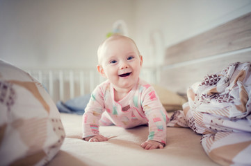 Baby infant on bed before sleeping. Child climbs the bed. Toddler having tummy time on bed.