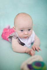 Adorable baby with bib in bed. Newborn child relaxing in bed. Newborn kid during tummy time smiling happily at home with family.