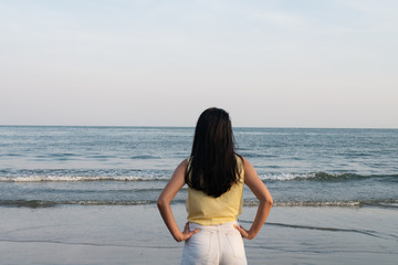 One woman girl is standing on the sandy beach seashore looking at the ocean wave for holiday lifestyle relaxation concept with copyspace background