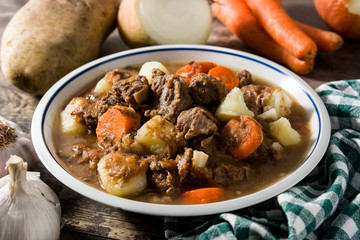 Irish beef stew with carrots and potatoes on wooden table