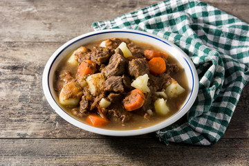 Irish beef stew with carrots and potatoes on wooden table