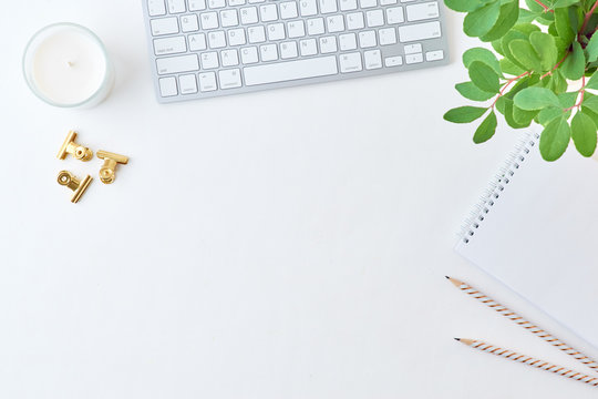 Blogger or freelancer workspace with keyboard, notebook and branches with green leaves on light background