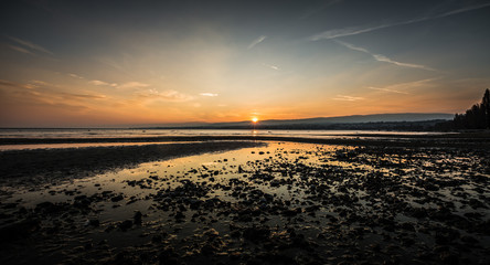 Sunset on the lake shore in stones, orange sky, natural colors