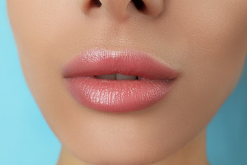 Woman with beautiful full lips on light blue background, closeup