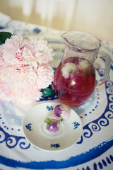 Home made lemonade with frozen ice ball with flower on little plate on white and blue table cloth