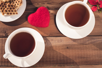 two cups of tea with heart-shaped cookies, top view on a rustic background. Valentine's Day