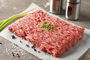 Spices and baking paper with minced meat on grey background, close up