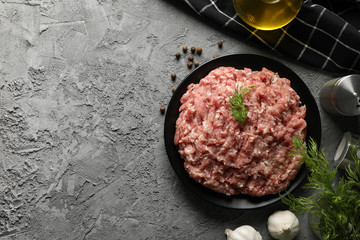 Spices and plate with minced meat on grey background, top view