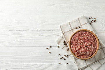 Towel, spices and bowl with minced meat on wooden background, top view