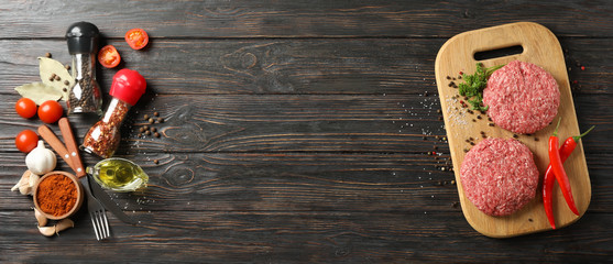 Spices and cutting board with minced meat on wooden background, space for text