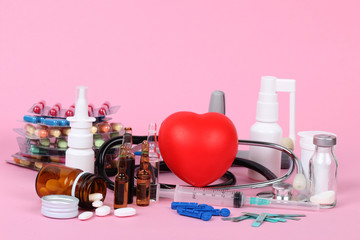 heart and stethoscope on a pink background with medical drugs