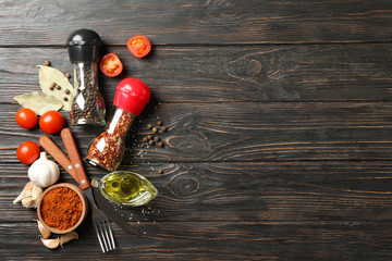 Pepper mills, spices and vegetables on wooden background, space for text