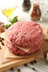 Spices and cutting board with minced meat on wooden background, close up