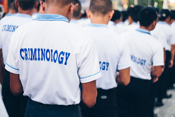 Rear view of men wearing white and blue polo shirt with Criminology text at the back. Selected focus. Copy space. 
