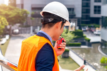Male Asian construction manager with using walkie-talkie at construction site.