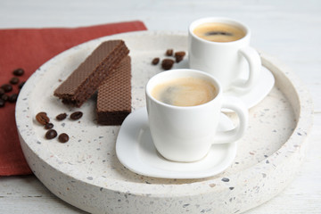 Delicious coffee and wafers for breakfast on white wooden table