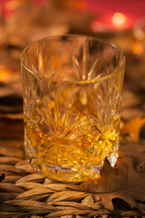 A glass of whiskey or bourbon, spices and decoration on dark background